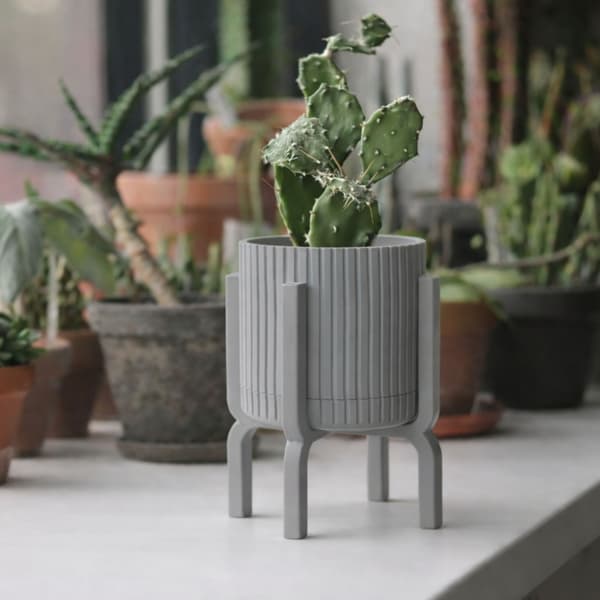 Modern, räfflad grå blomkruka med växtställ