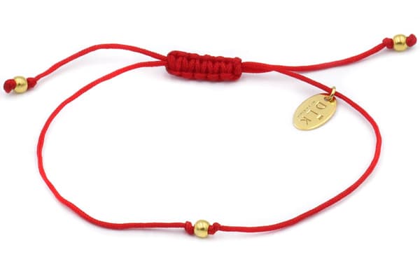 Rött snörearmband med en guldkula
