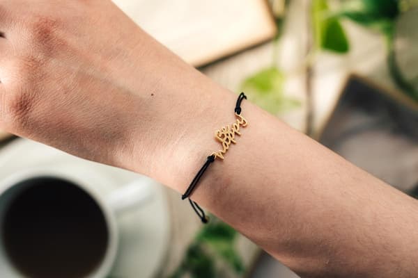 Snörearmband med texten BE HAPPY i guld