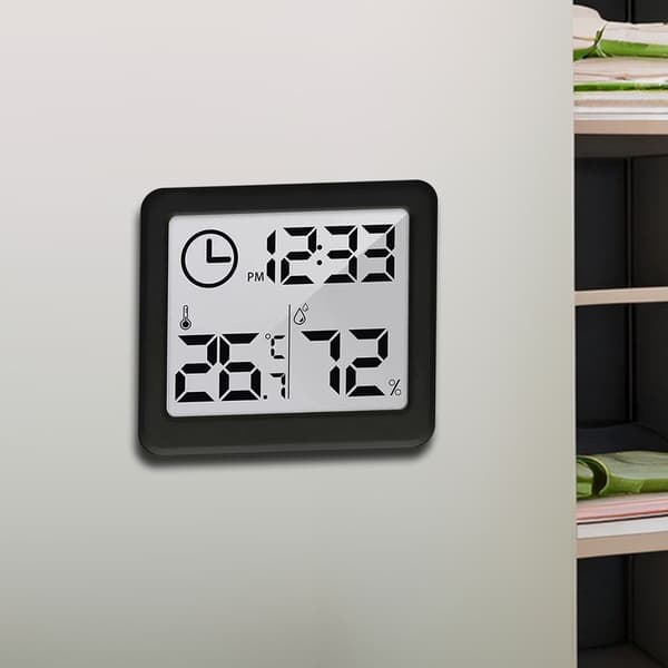 Digitalt termometer og hygrometer med urfunktion, der viser omgivelsestemperatur og luftfugtighed (sort).
